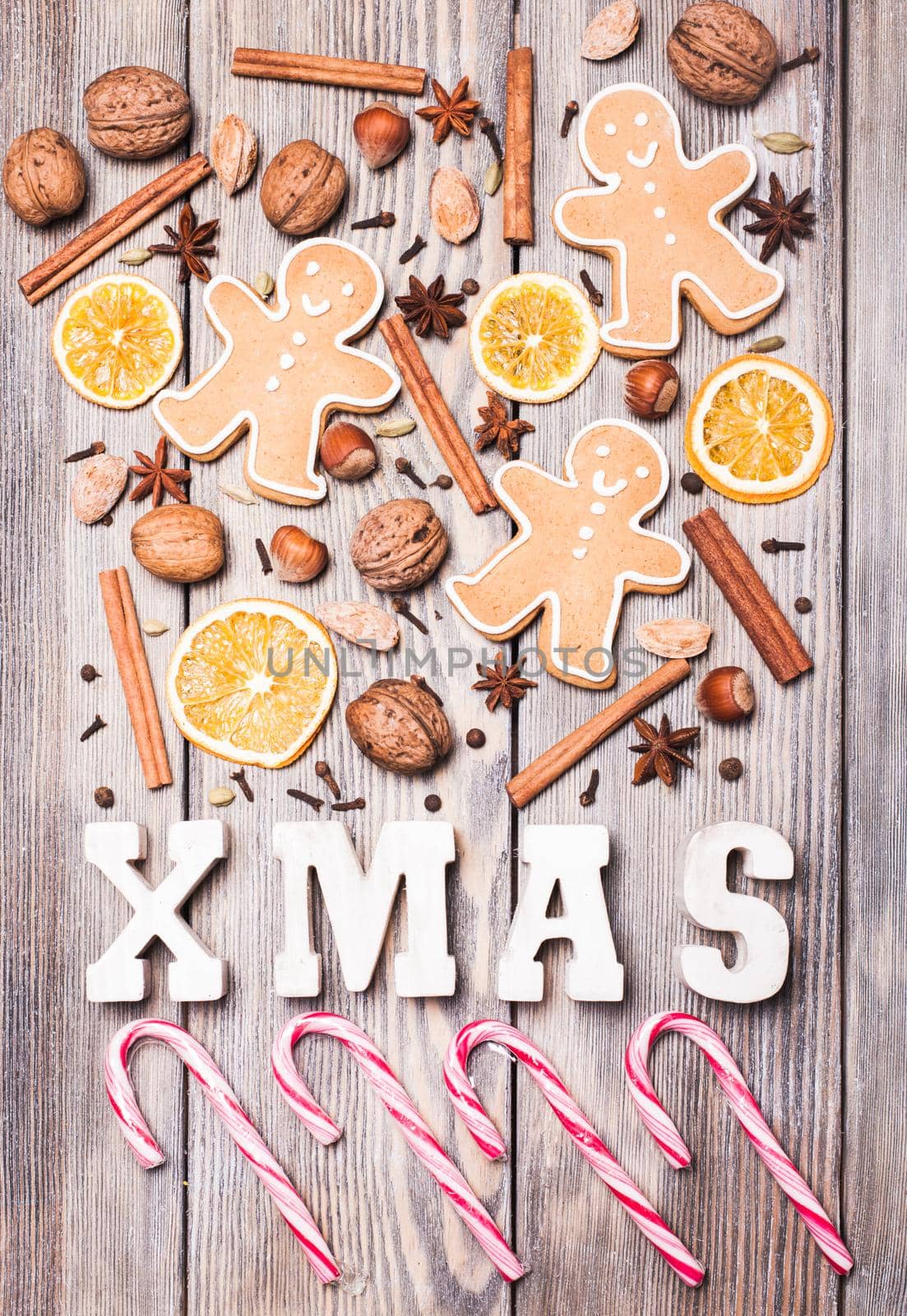 Gingerbreads with spices on the wooden table, wooden letters XMAS and Santa staffs candies. Christmas aroma decor