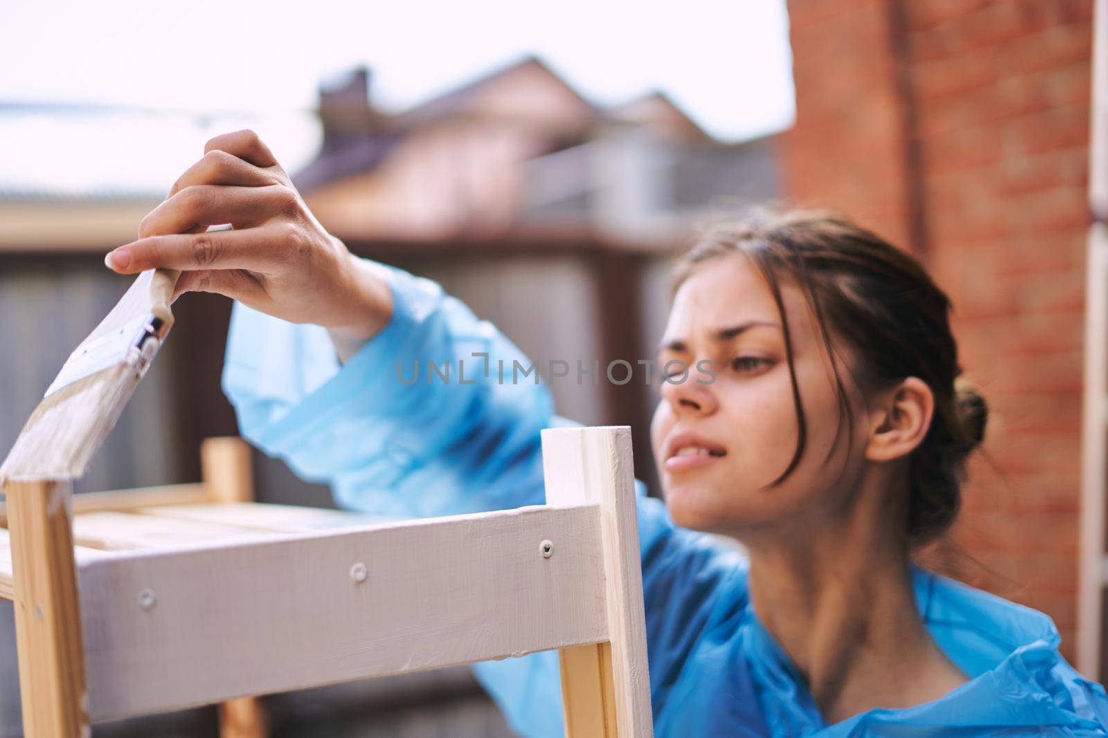 cheerful woman with a paint brush to paint wooden fittings by Vichizh