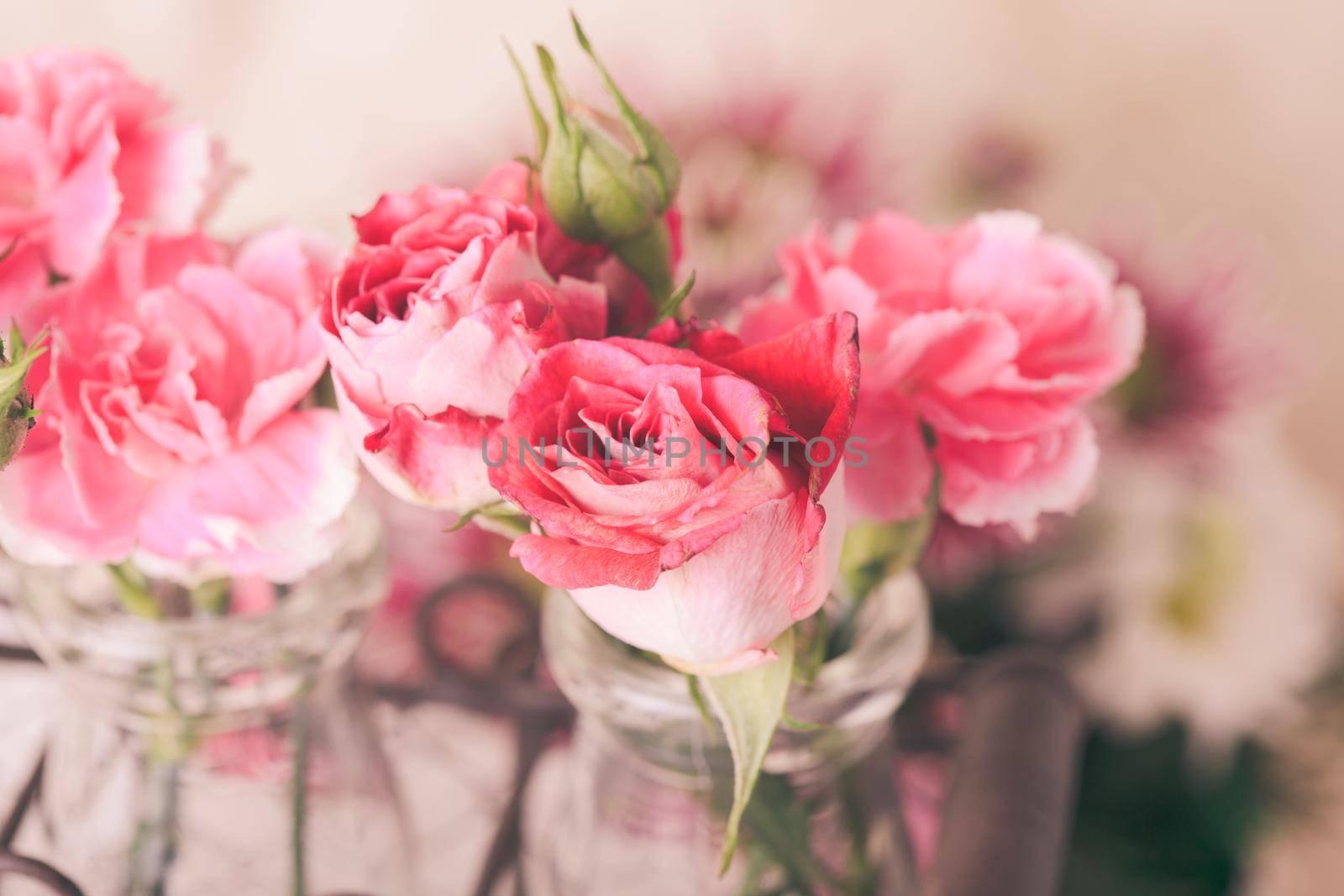 Pink flowers in glass bottles in metal basket. Vintage decor concept