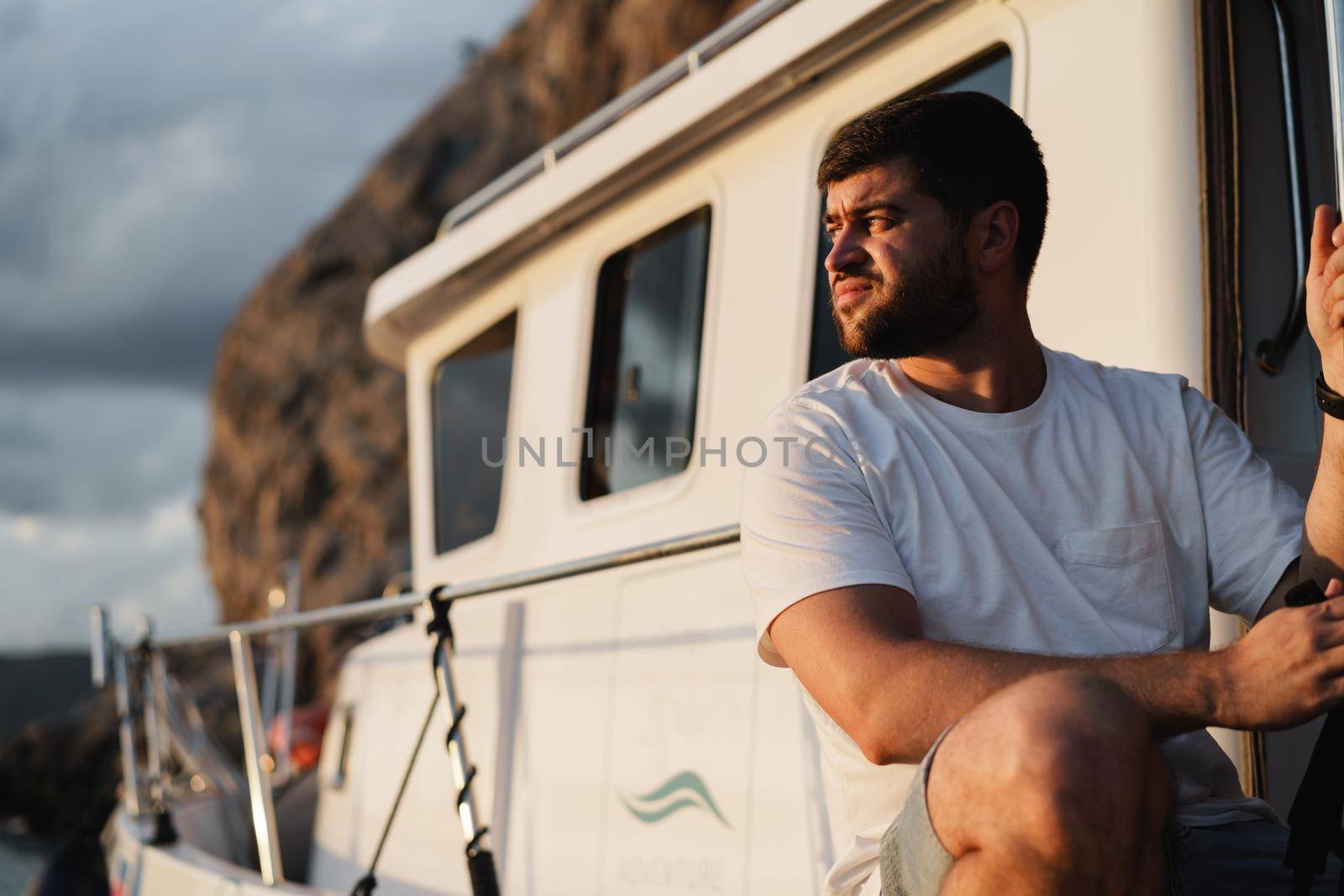 Portrait of a young caucasian bearded man sitting on a deck of sailboat, close up