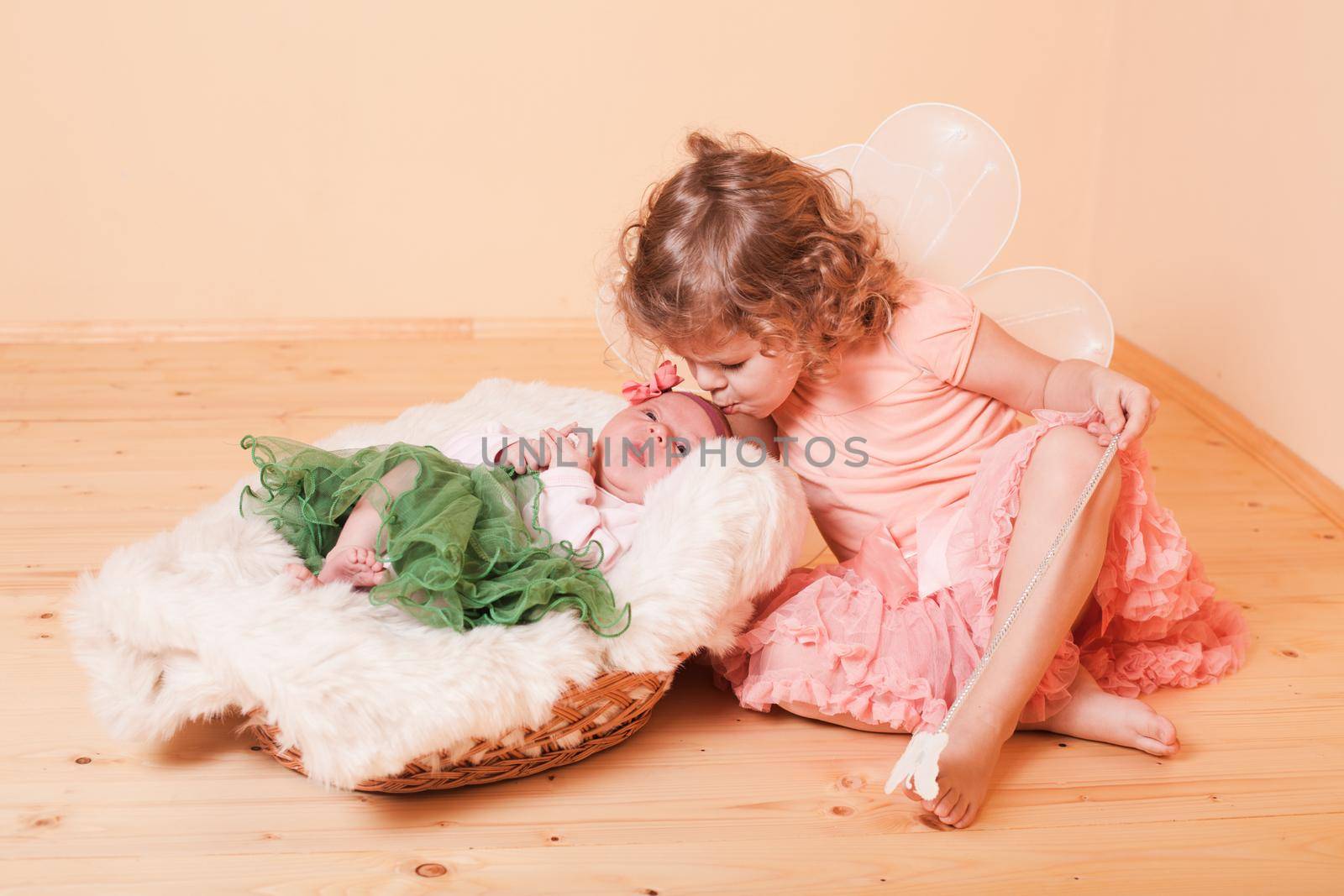 Little girl with her newborn sister in a basket