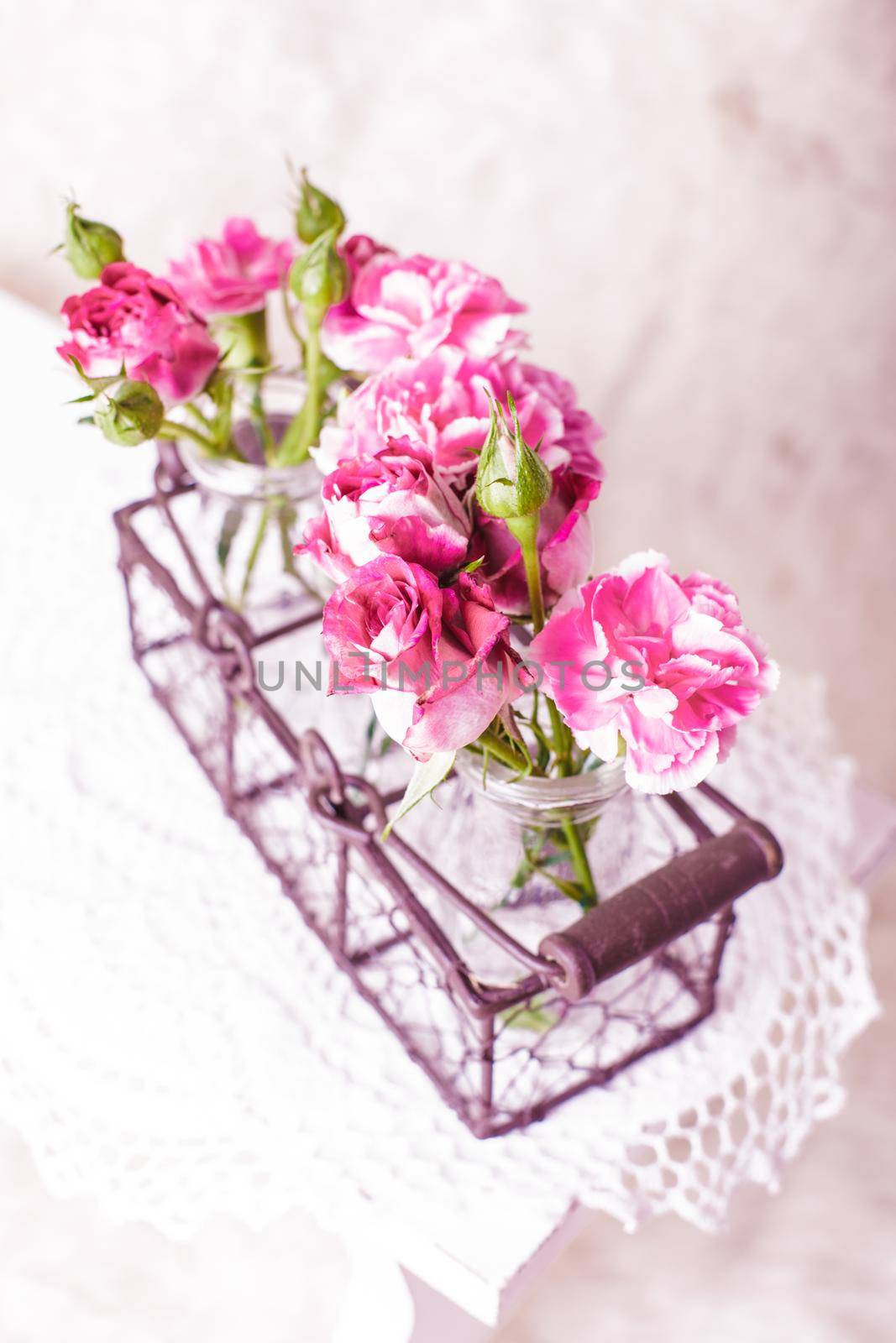 Pink flowers in glass bottles in metal basket. Vintage decor concept