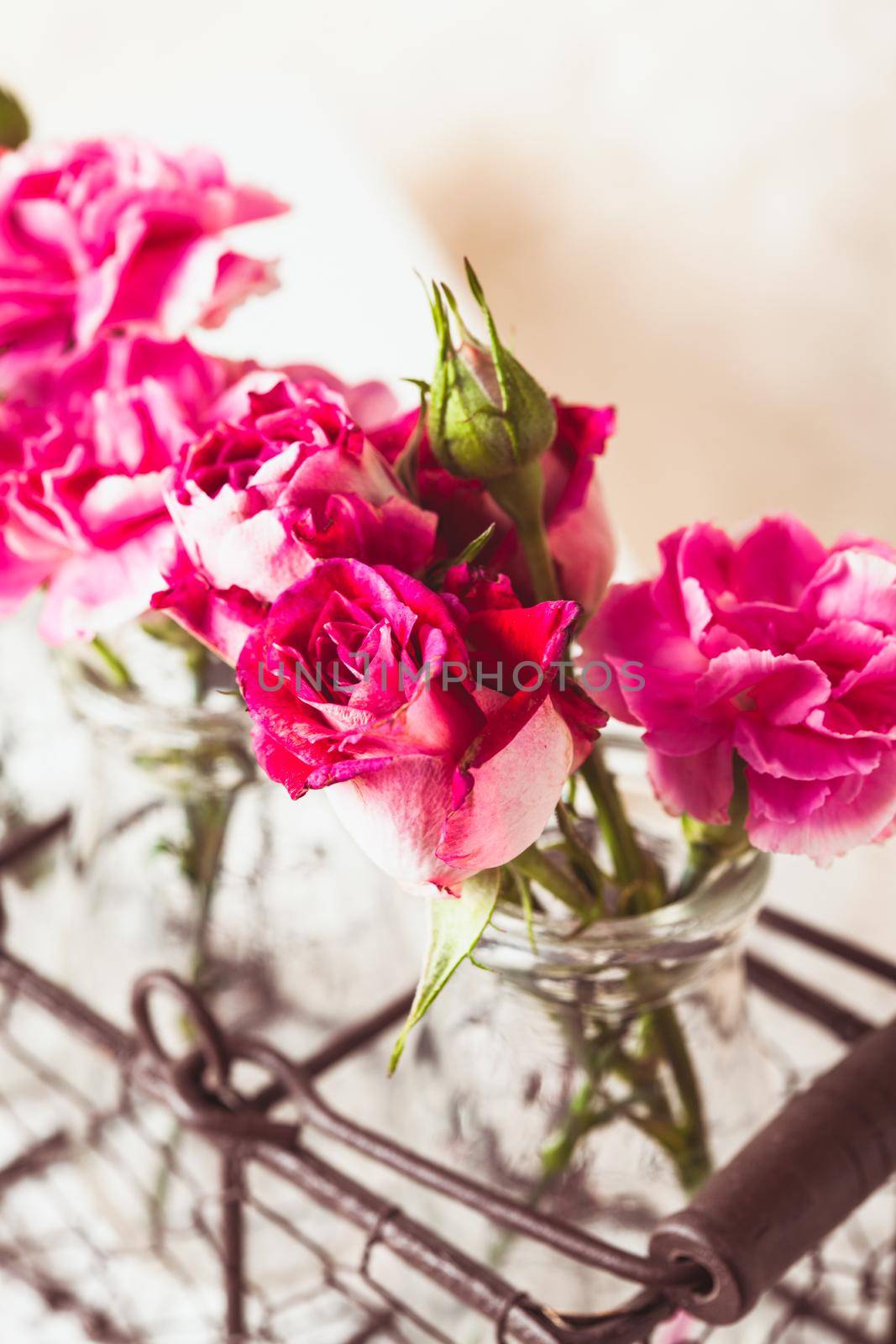 Pink flowers in glass bottles in metal basket. Vintage decor concept