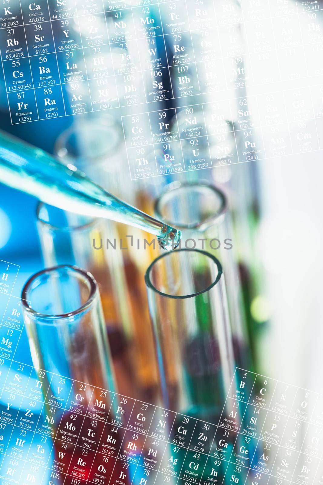 The blue drop from pipette over laboratory tubes and periodic table background