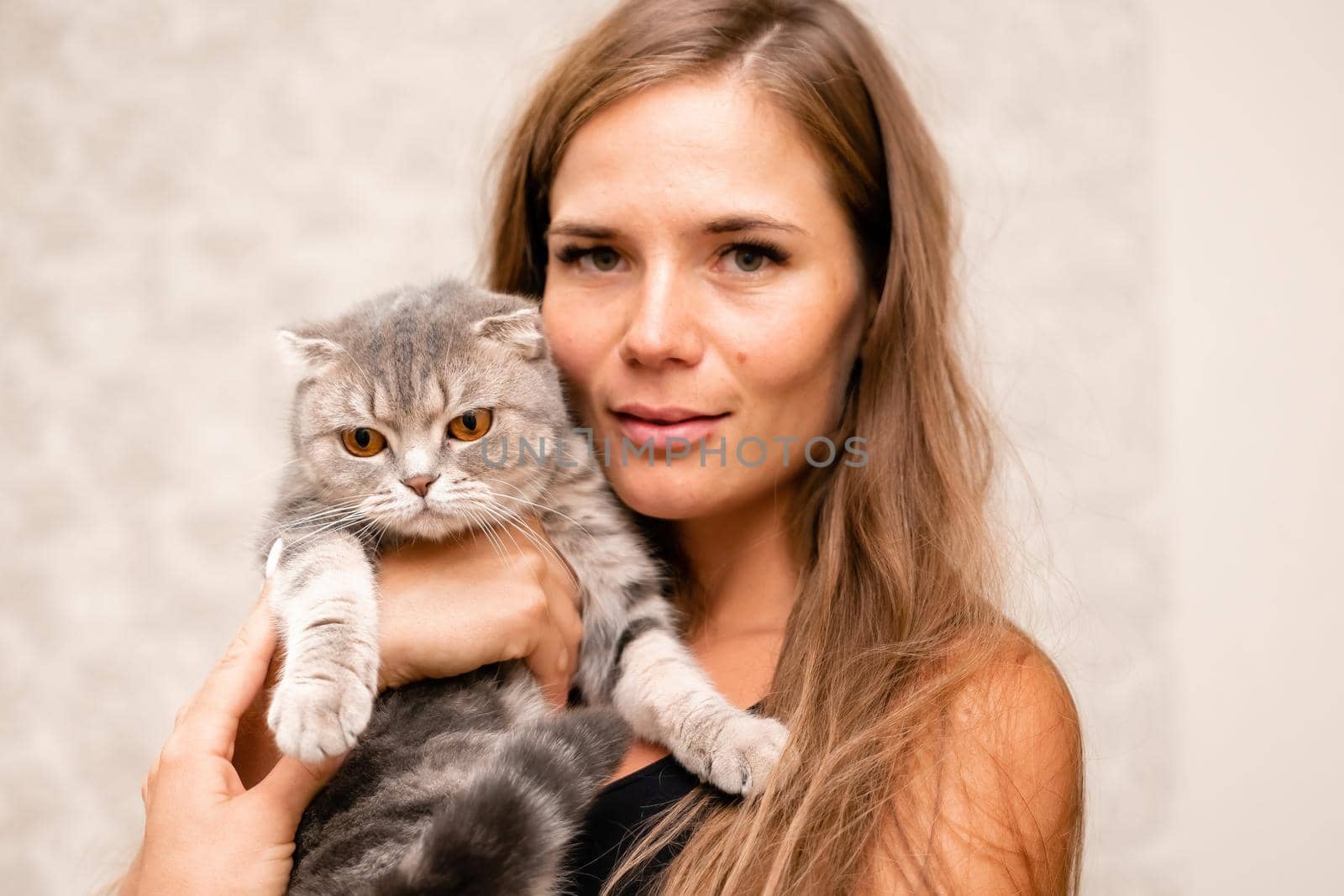 Attractive girl embracing her pet with smile. Indoor portrait of cute ginger woman playing with cat.