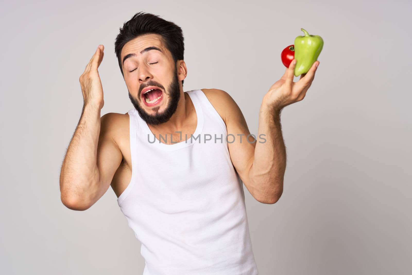 a man in a white t-shirt with vegetables in his hands healthy food diet. High quality photo