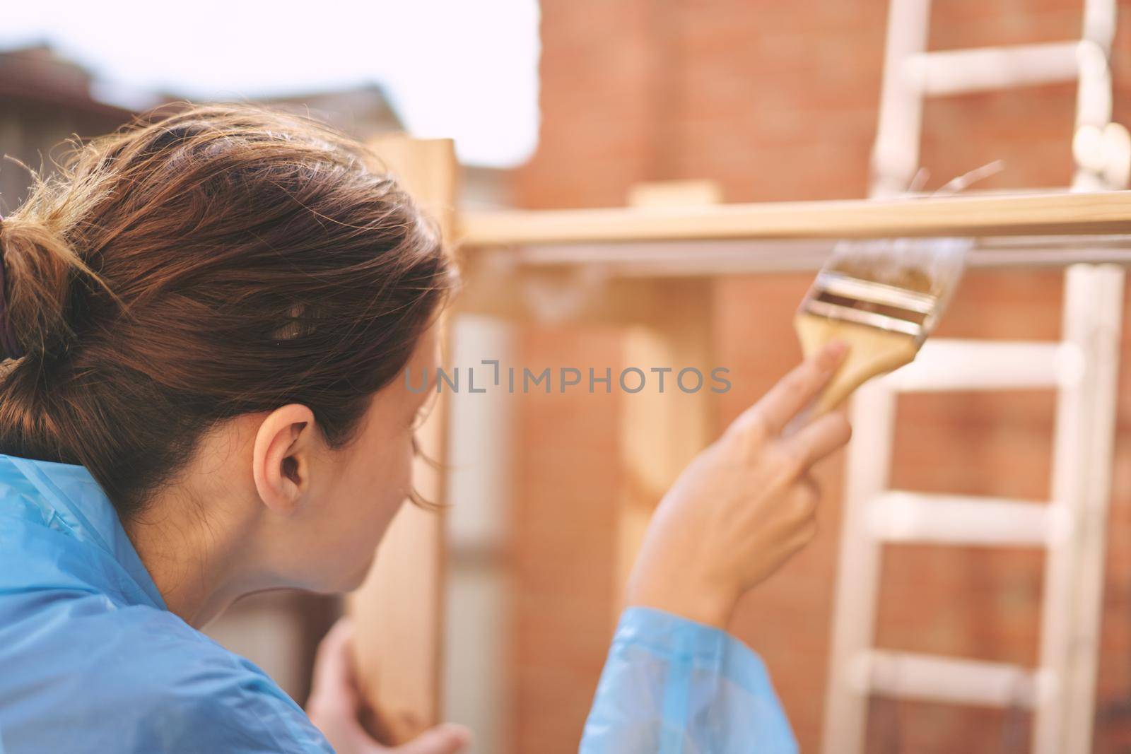 woman house painter renovating wood fittings at home by Vichizh