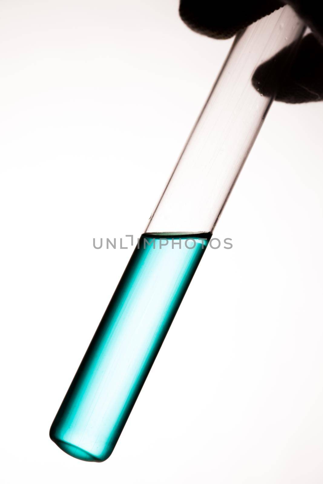 Laboratory glass tube with green liquid on white