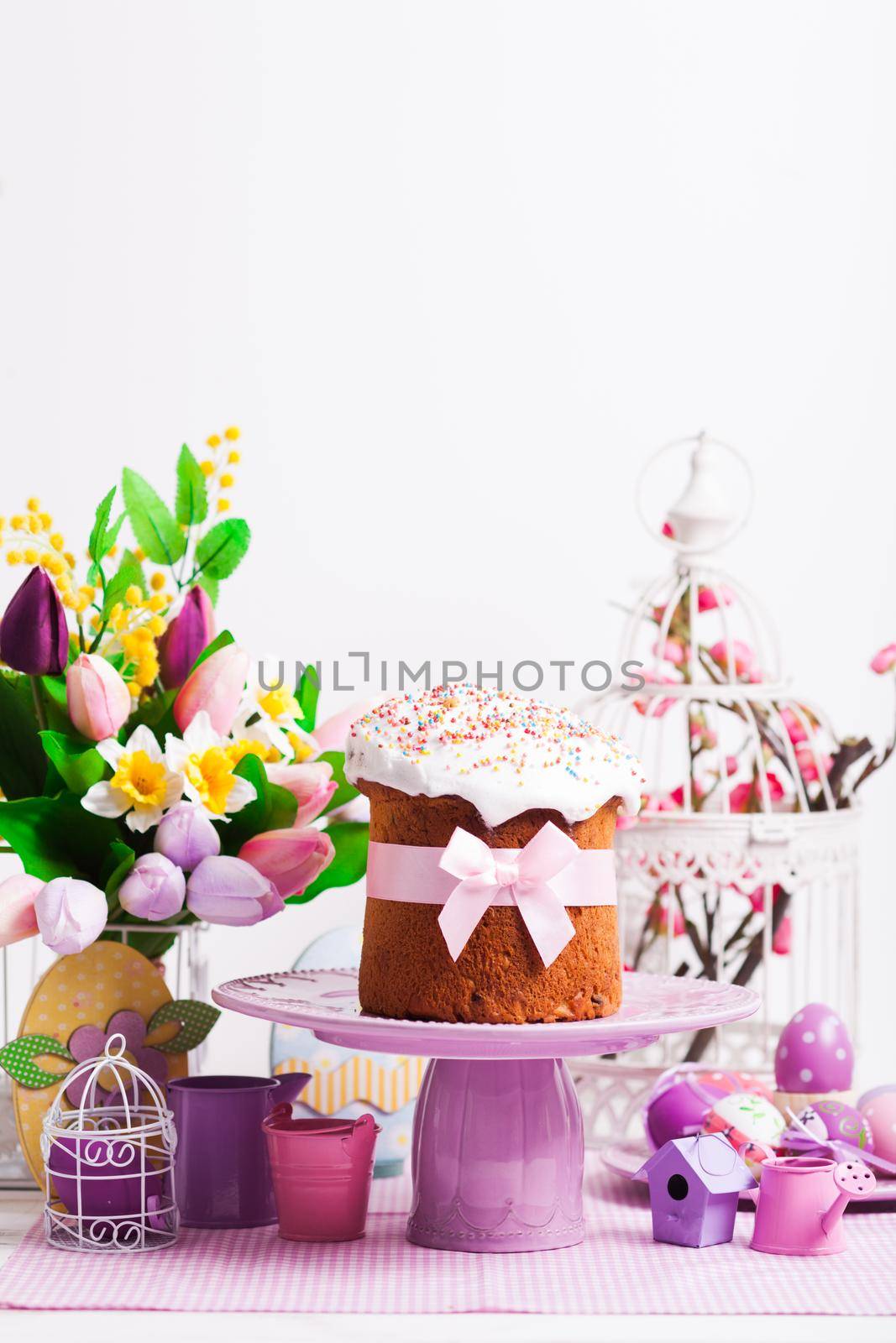 Easter cake on the cake stand and flowers, lilac desorations on the foreground with copy space