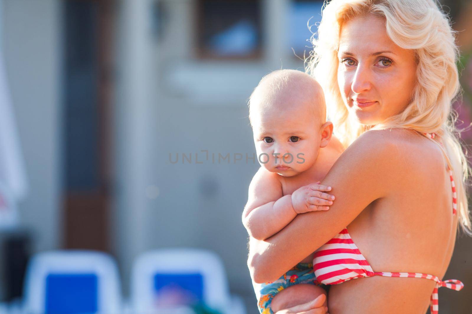 Pretty young mom with baby at the swimming pool