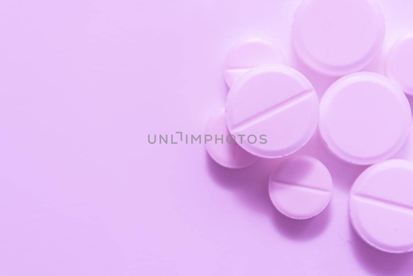 White-pink pills on a soft pink background. Selective focus.