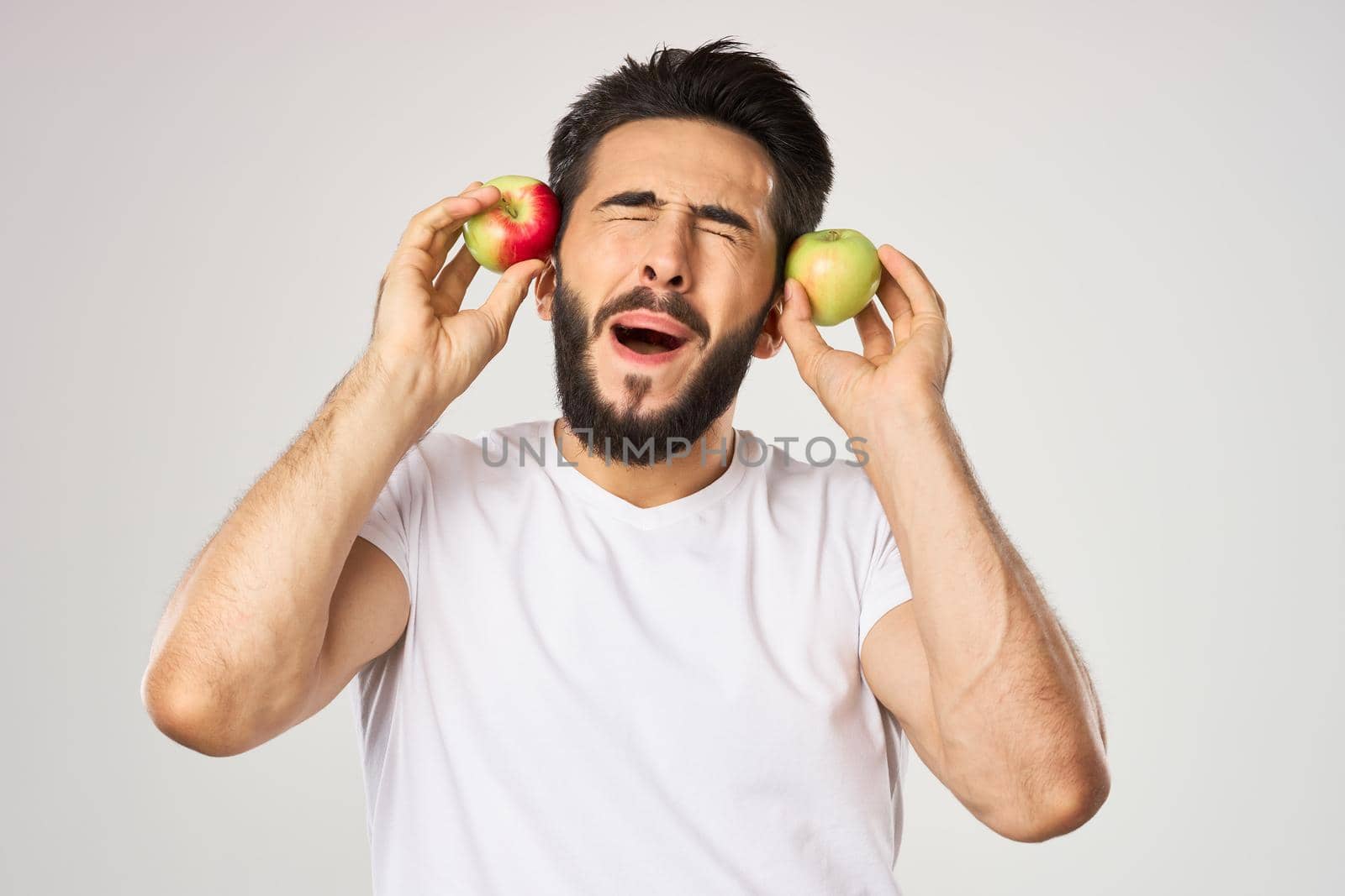 Cheerful man with apples in his hands in a white t-shirt fruits. High quality photo