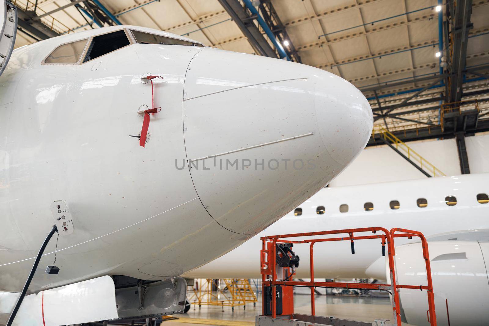 Close up shot of fuselage of modern passenger airplane on maintenance repair check in airport hangar indoors. Aircraft. Plane, shipping, transportation concept