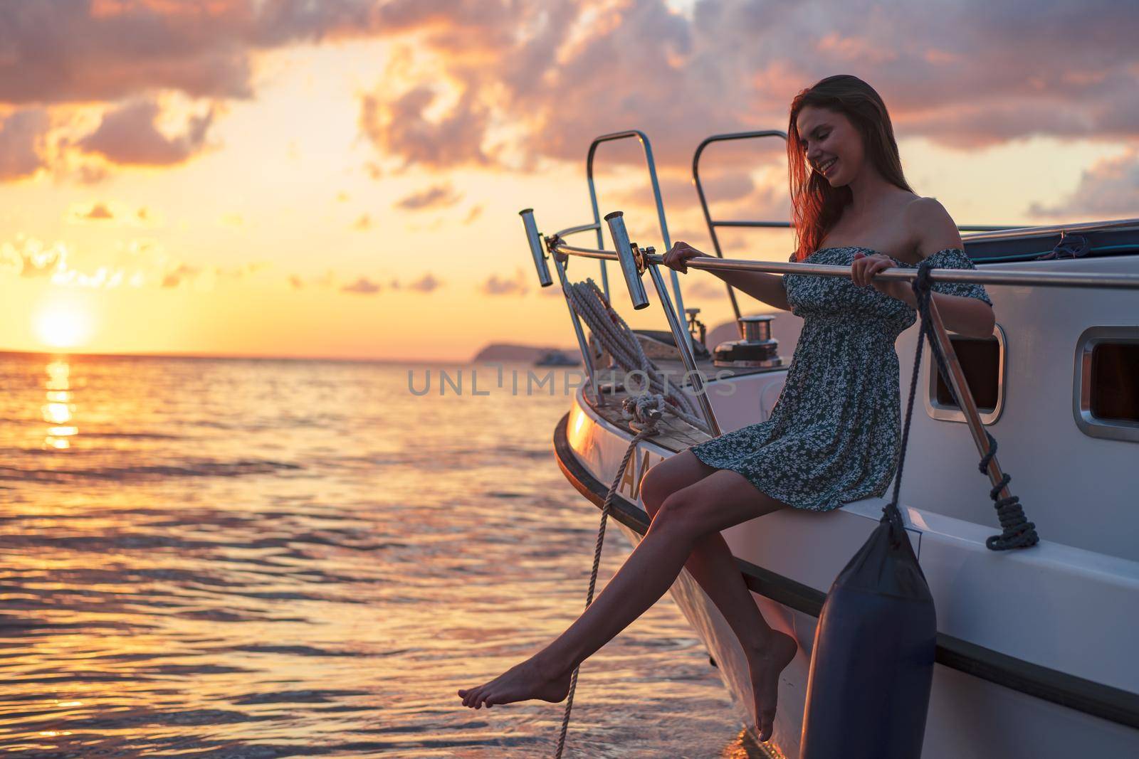 Young attractive woman sitting on the deck of the yacht and enjoying sunset