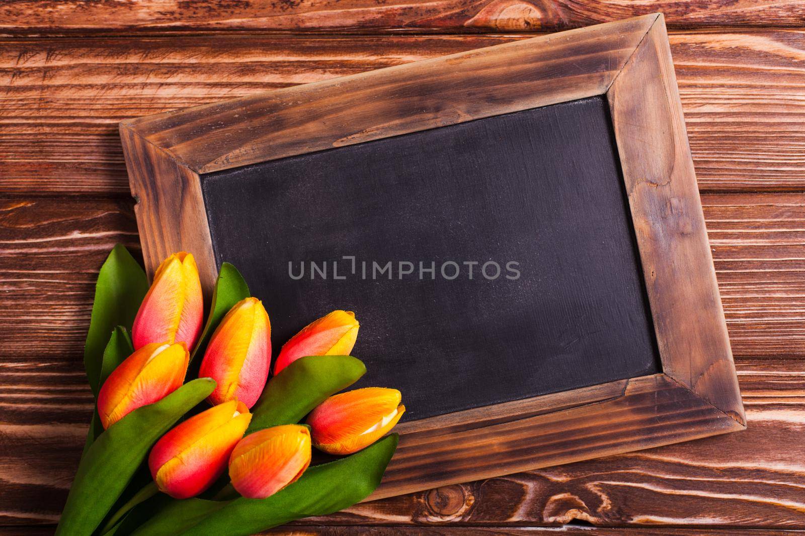 Tulips with chalkboard on a wooden background - spring greetings