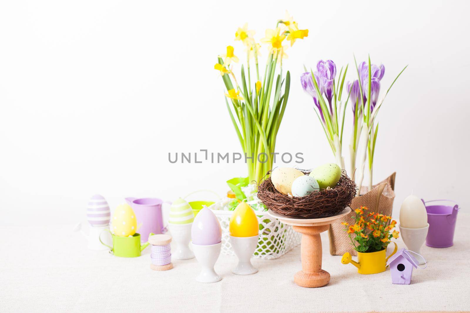 Easter decorations - egg candles, nest and flowers on the table