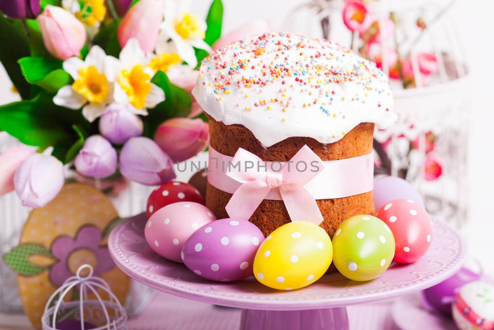 Easter cake and colorful polka dot eggs on the plate and flowers on the foreground