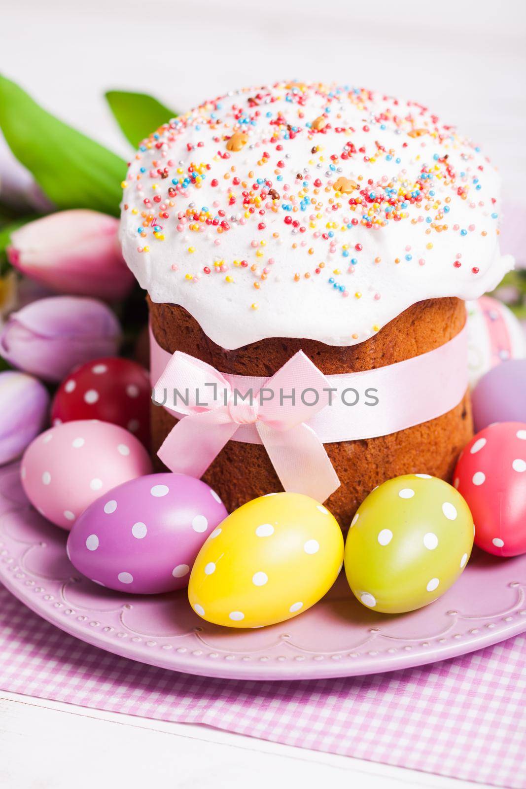 Easter cake and colorful polka dot eggs on the plate and flowers on the foreground