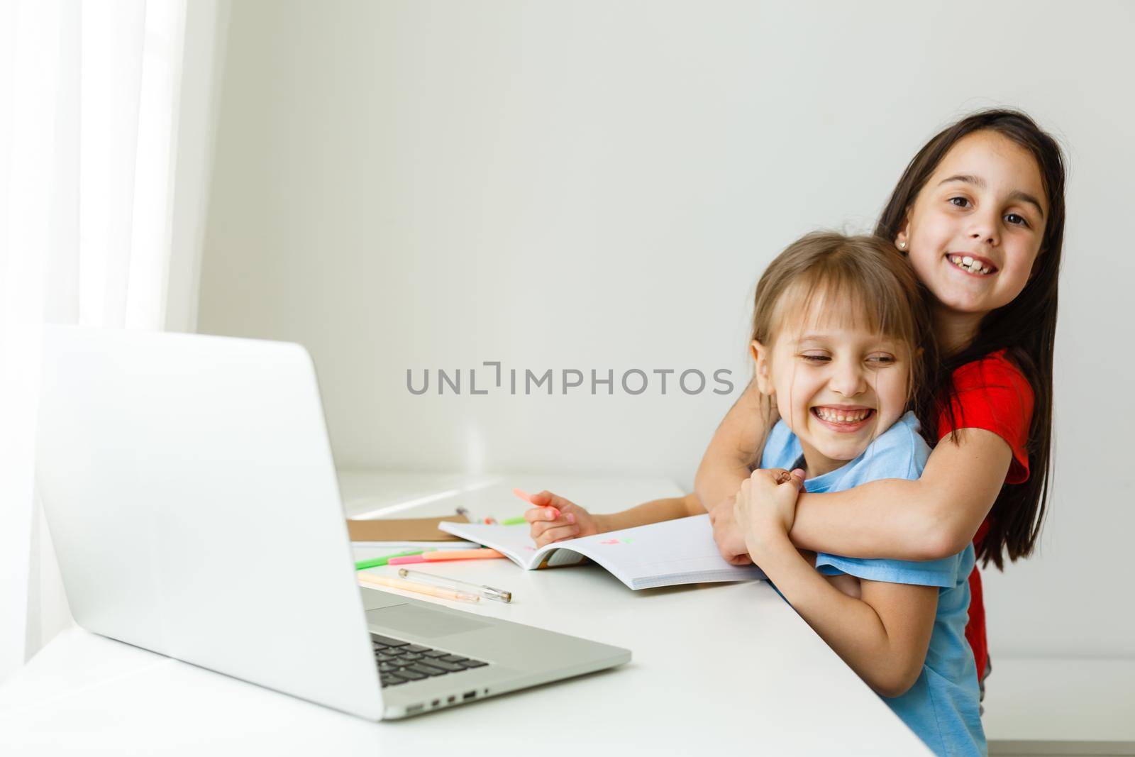 Cool online school. Kids studying online at home using a laptop. Cheerful young little girls using laptop computer studying through online e-learning system. Distance or remote learning