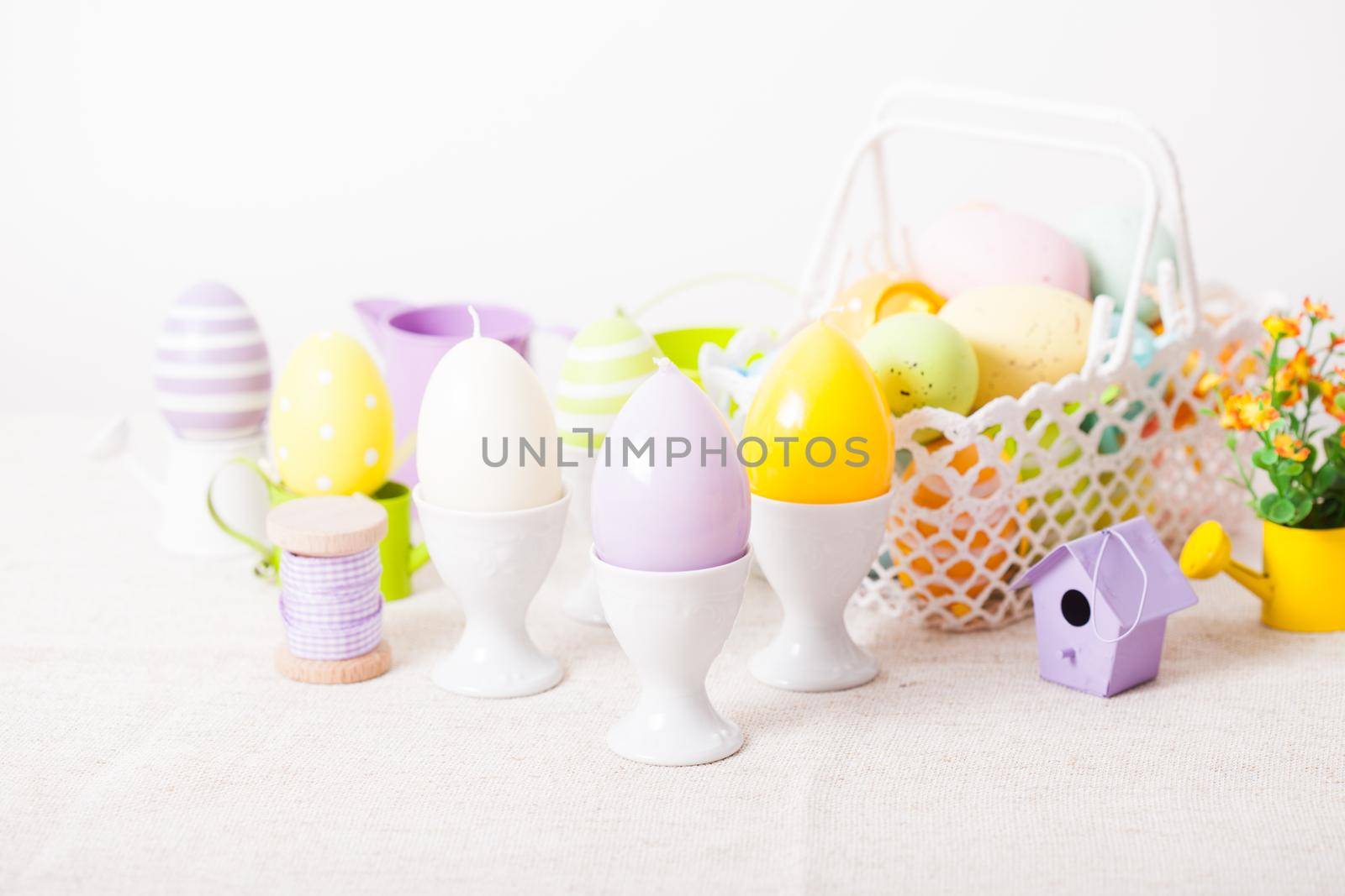 Easter decorations - egg candles, nest and flowers on the table