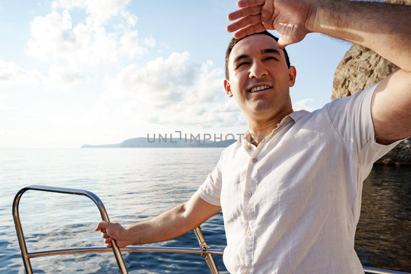 Young man in white shirt standing on the nose yacht in the open sea