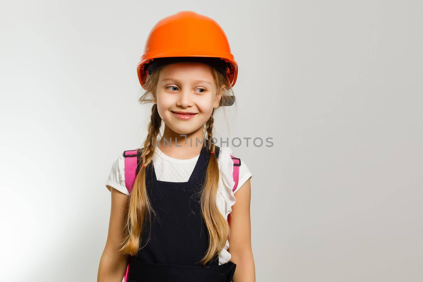 Cute little girl is isolated on white background. Girl looking at camera, wearing yellow helmet by Andelov13