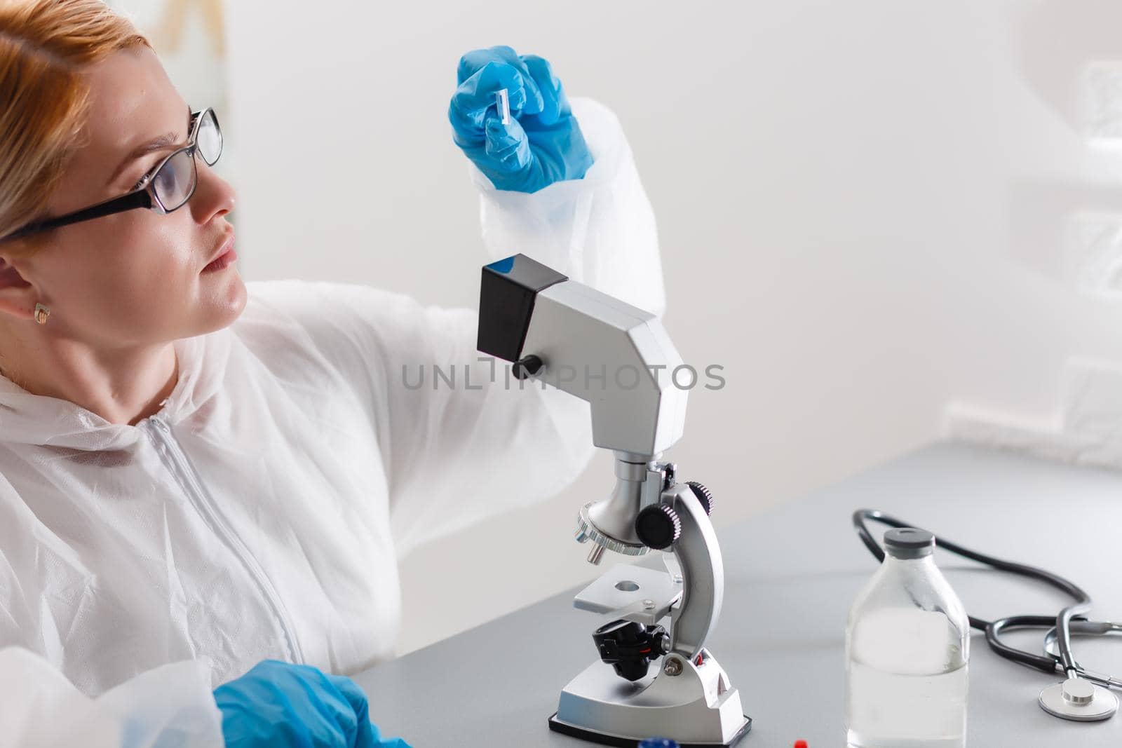 A beautiful female medical or scientific researcher using her microscope in a laboratory.