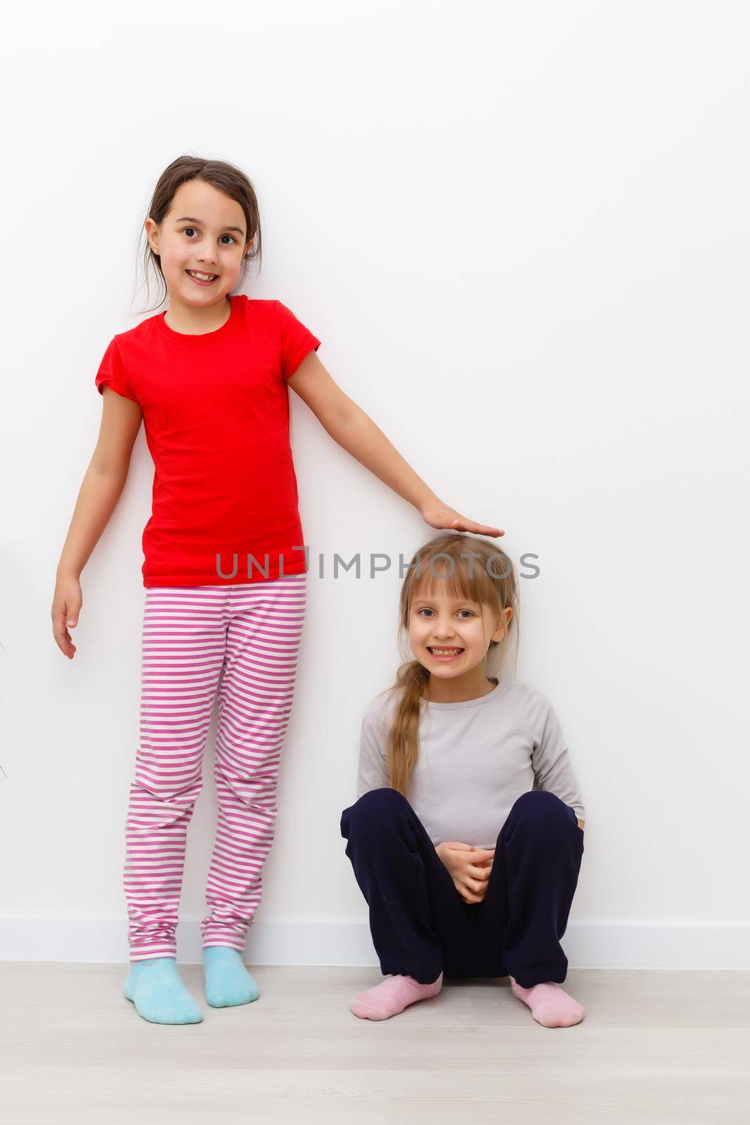 Two cute little girls in full growth, in the studio on a white background. The concept of a happy childhood, Beauty and fashion. Isolated.