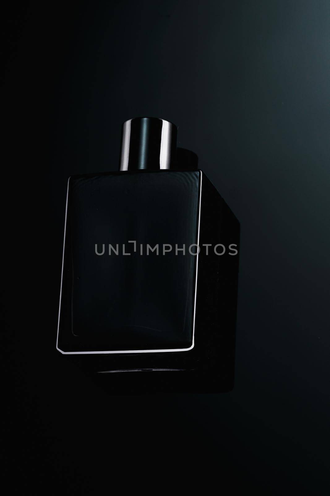 Silhouette of a black bottle of eau de toilette for men on a dark background. Advertising photo of perfumes. Dark style by SergeyPakulin
