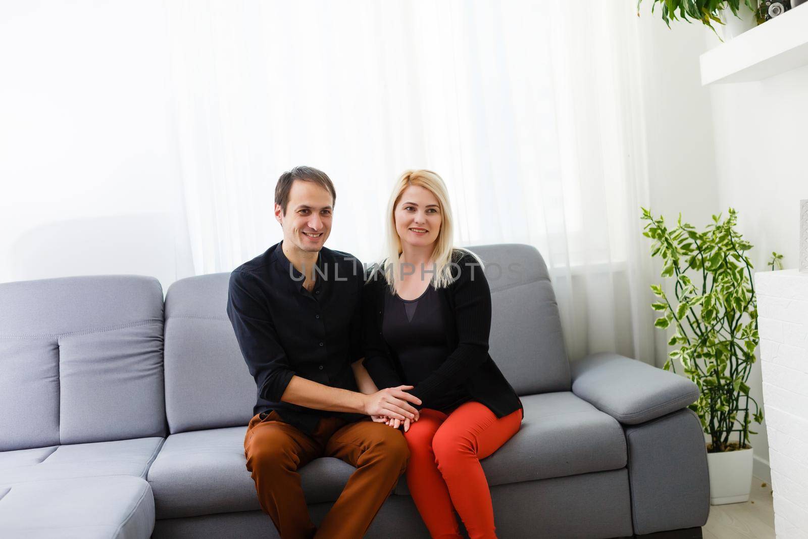 Happy young couple is hugging and smiling while sitting on the couch at the psychotherapist.