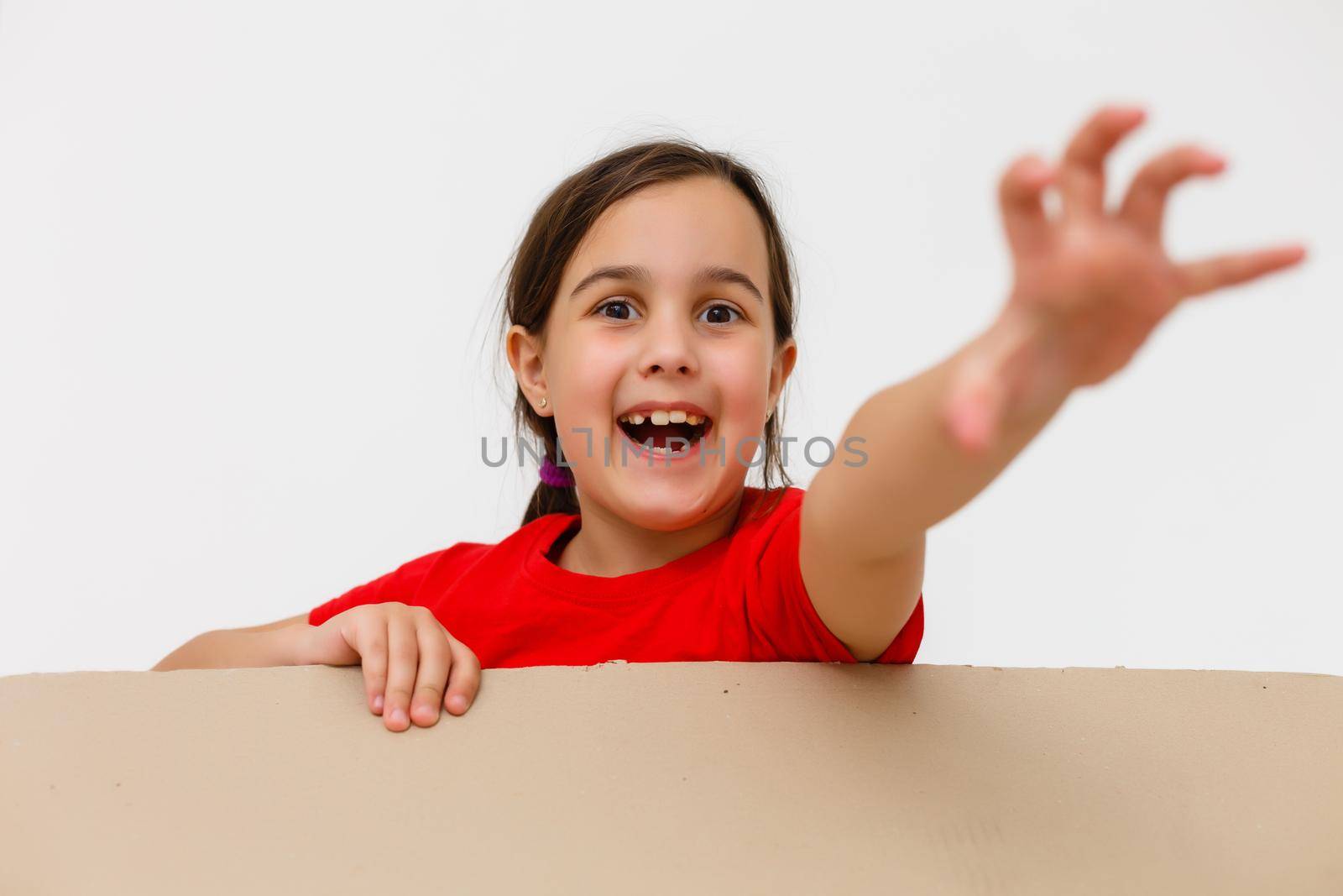 Cute little girl standing in large cardboard box, wanting to play hide-and-seek