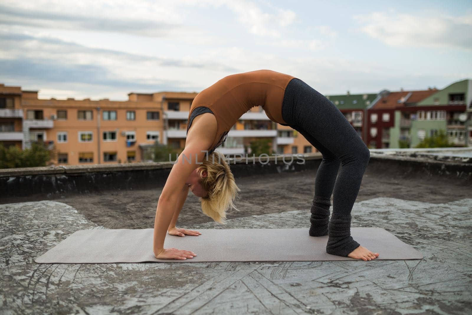 Woman enjoys practicing yoga on the roof,Urdhva Dhanurasana/Upward bow pose.