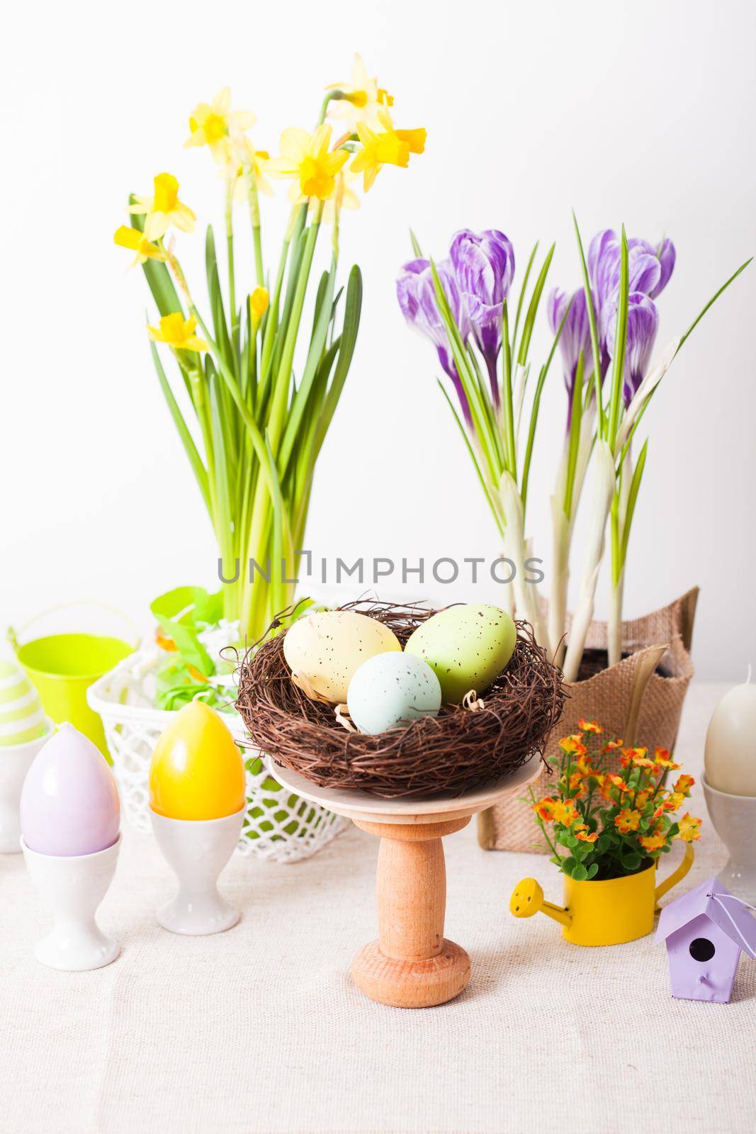 Easter decorations - egg candles, nest and flowers on the table