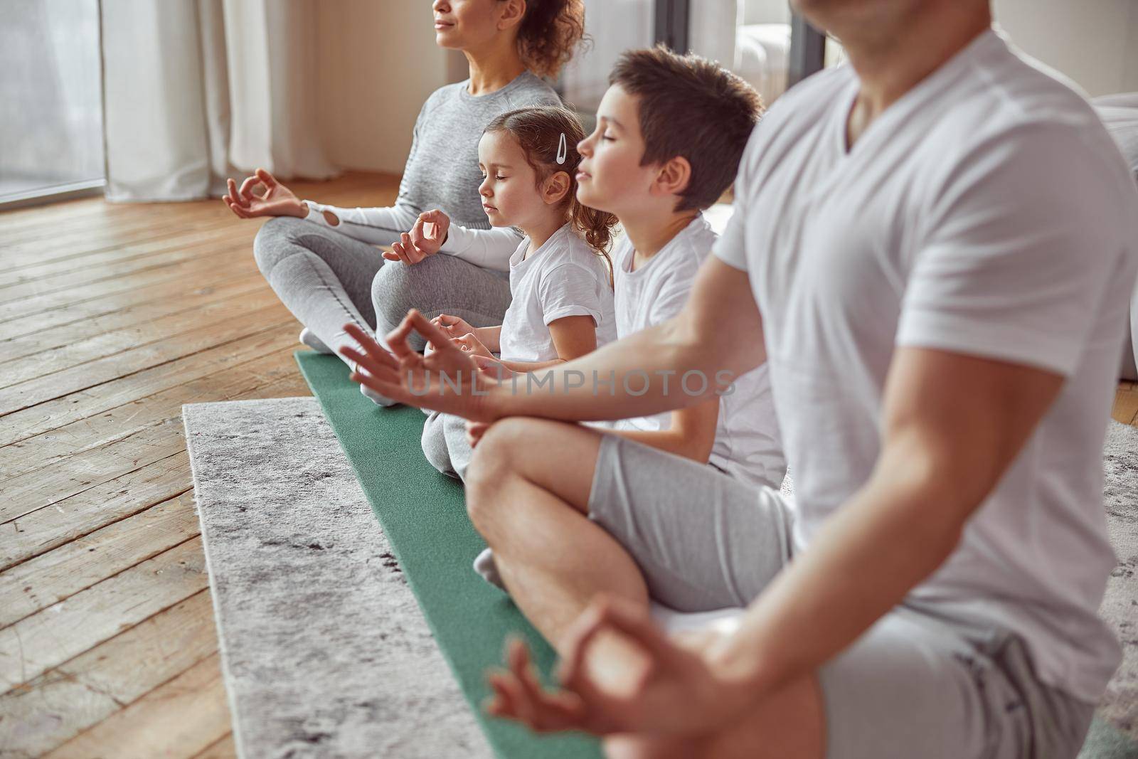 Parents doing meditation with kids at home by Yaroslav_astakhov