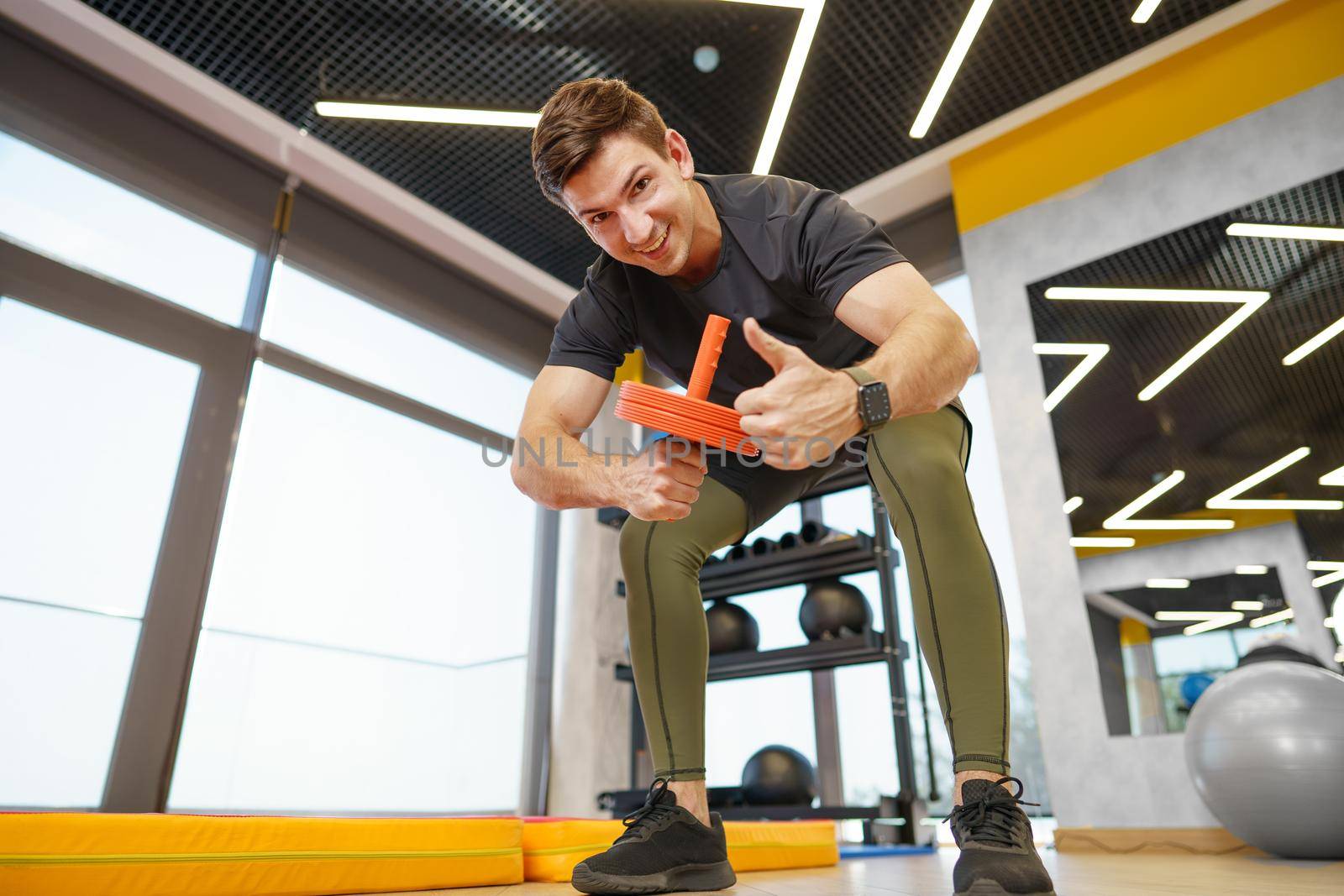 Athlete sporty man doing exercise with abs roller wheel in a gym