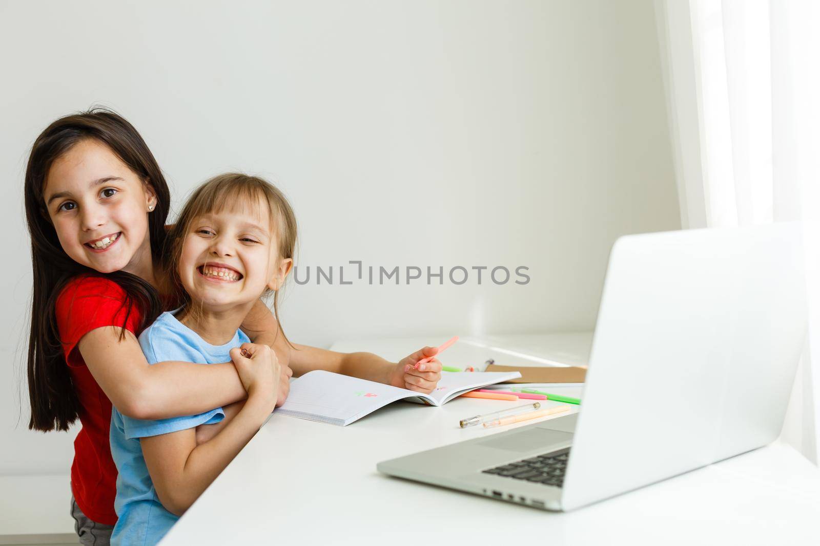 Two cute little sisters study together at home. Education for kids.