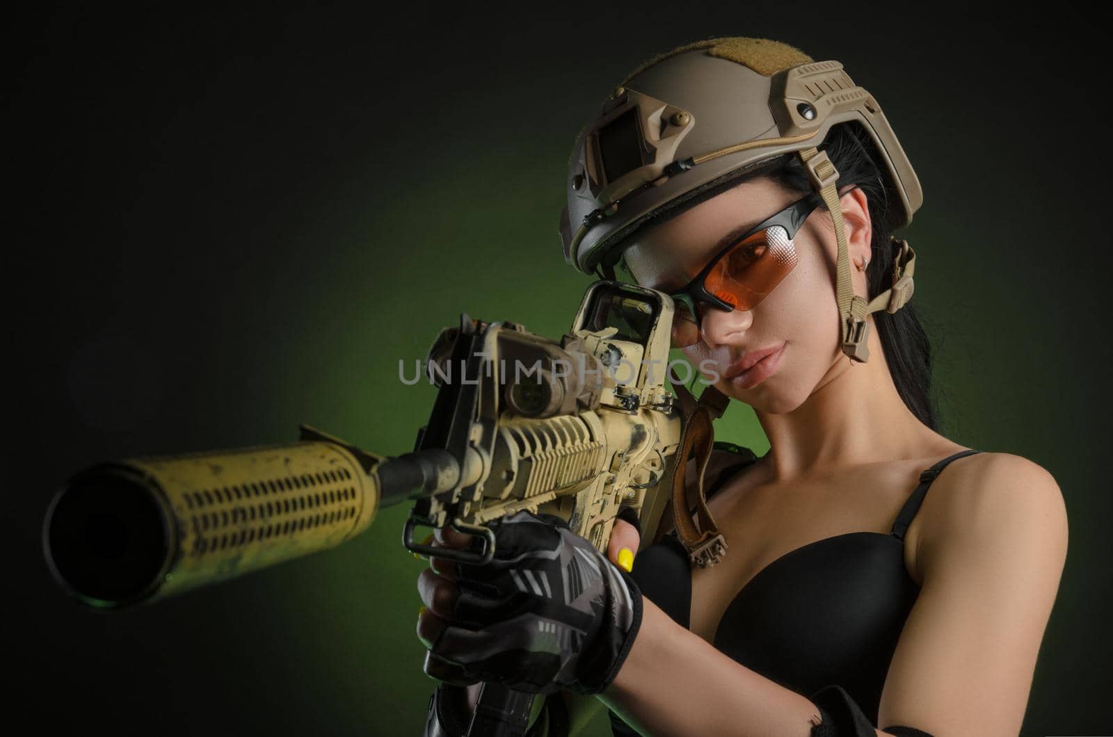 girl in military overalls airsoft posing with a gun in his hands on a dark background in the haze