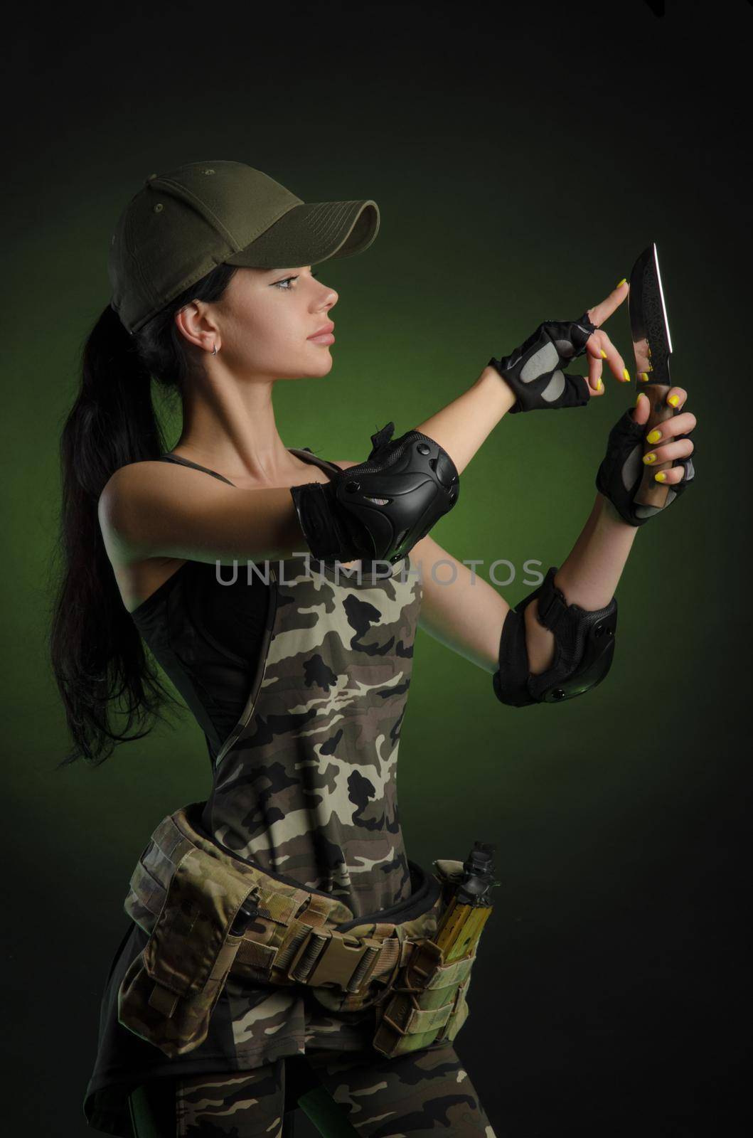 girl in military overalls airsoft posing with a gun in his hands on a dark background in the haze