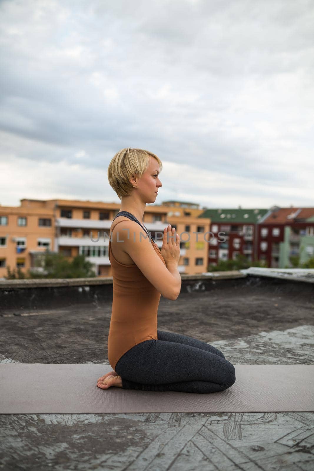 Woman enjoys  practicing yoga on the roof of a building.