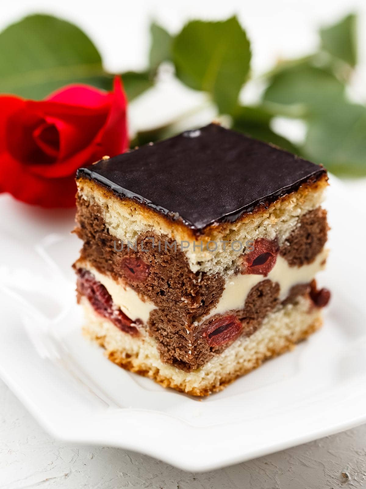 Cherry Cake with Chocolate Glazing. Piece of Cake on a Plate with red rose on the background. Romantic dinner concept