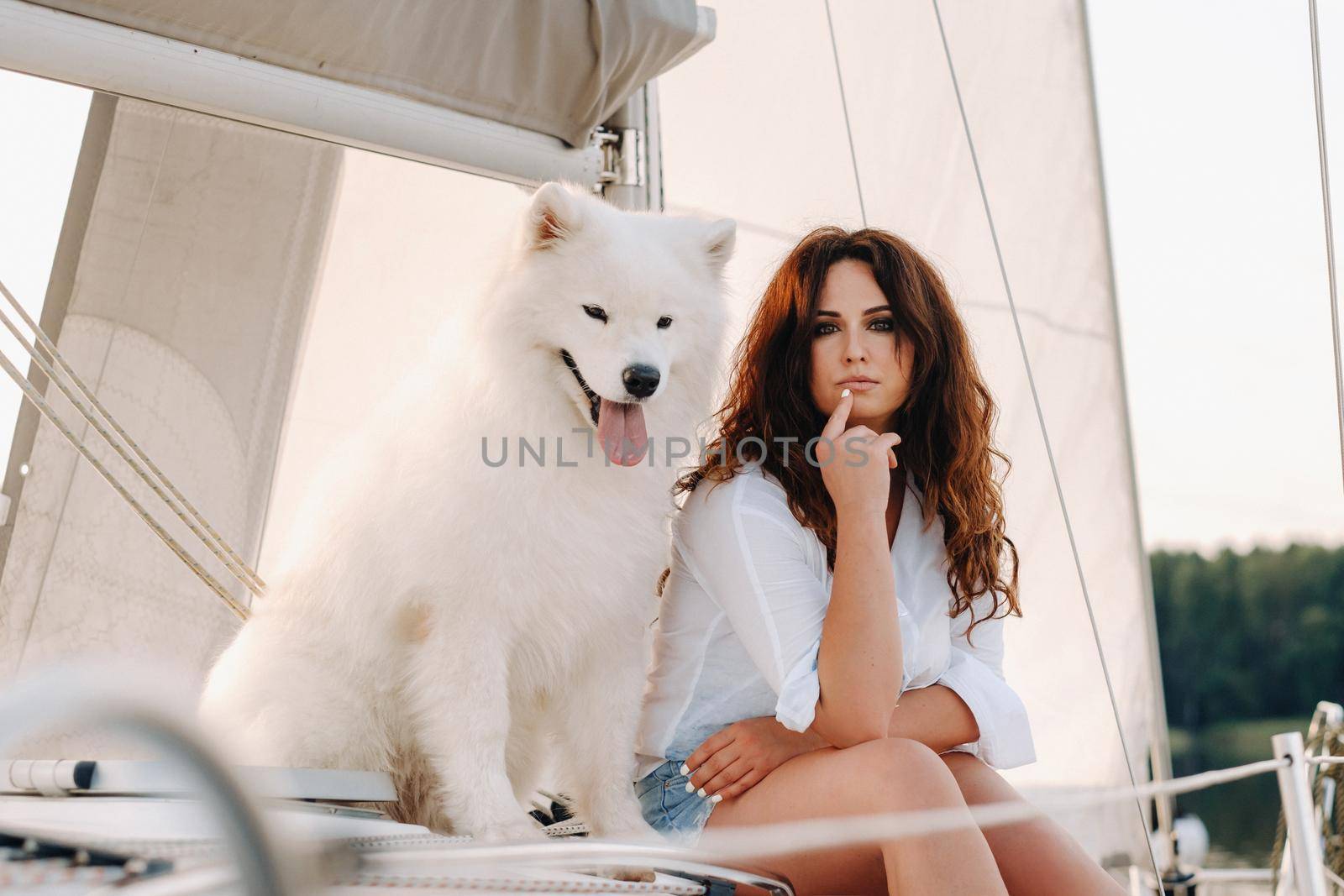 a happy woman with a big white dog on a white yacht in the sea.