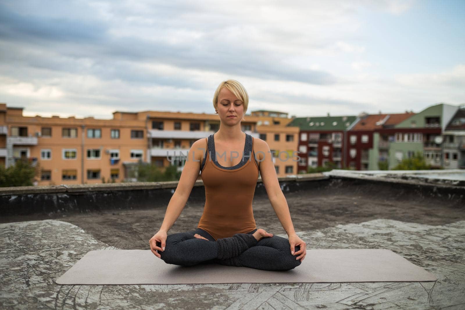 Woman enjoys practicing yoga on the roof,Ardha Padmasana/Half-lotus pose
