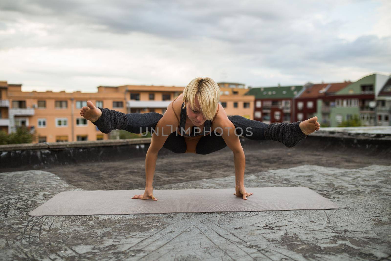 Woman enjoys practicing yoga on the roof,Tittibhasana /Firefly Pose.