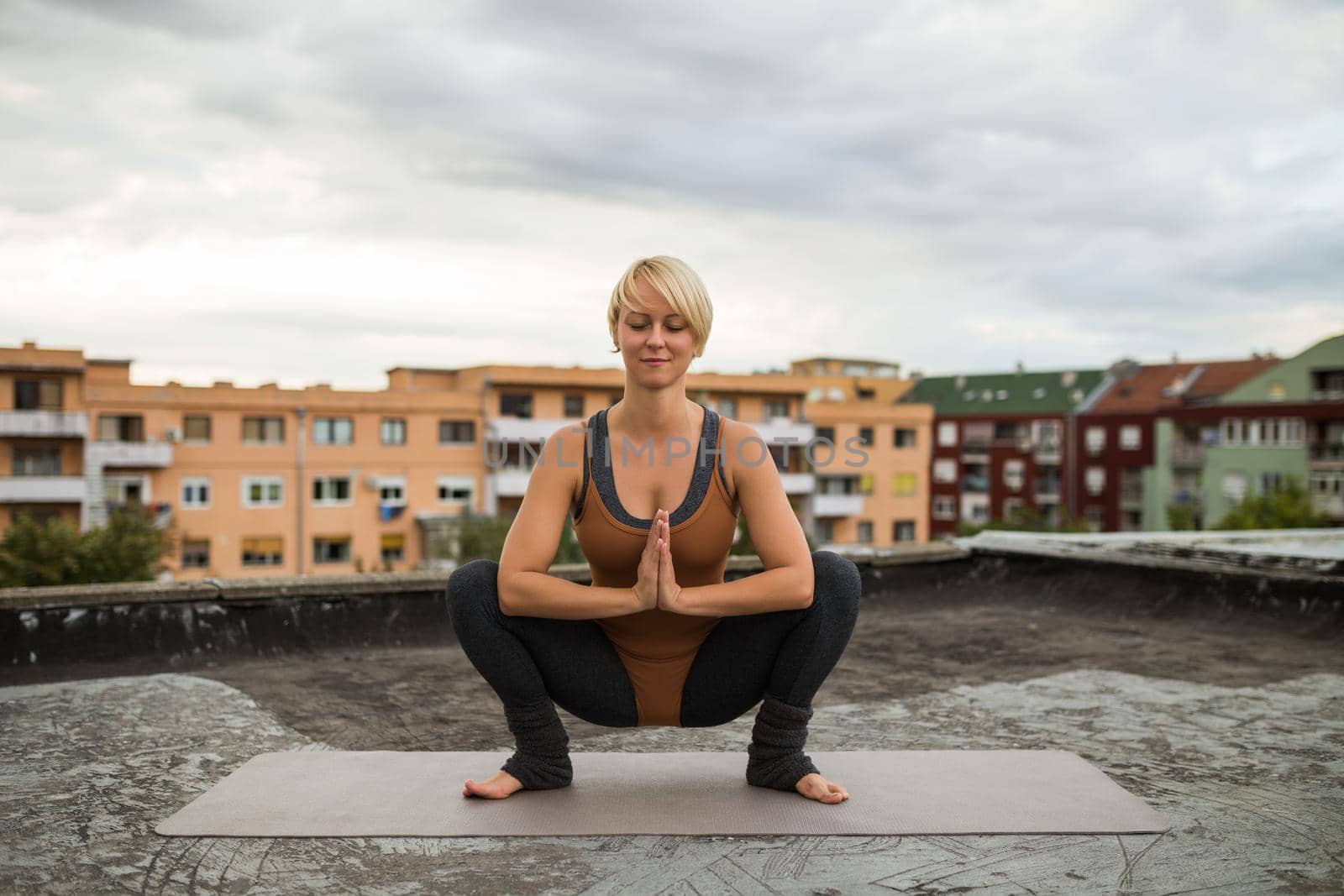 Woman enjoys practicing yoga on the roof, Utkatasana/Buddhist stupa pose