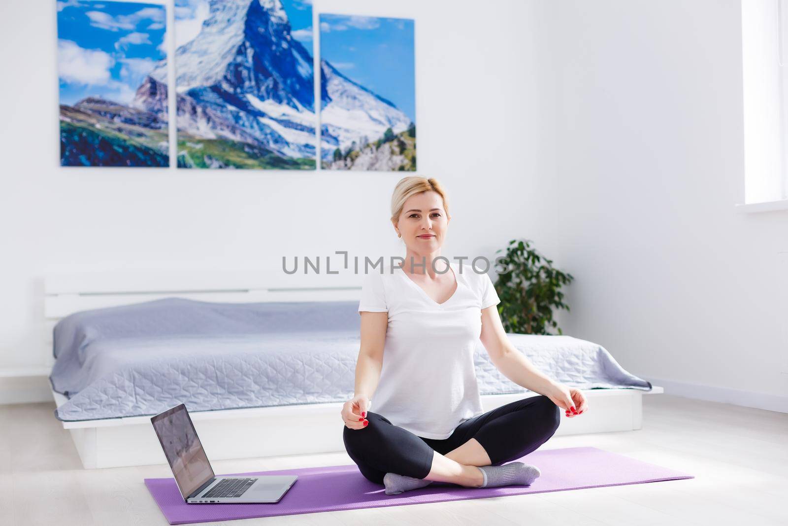Happy woman doing exercise while watching workout video on laptop at home