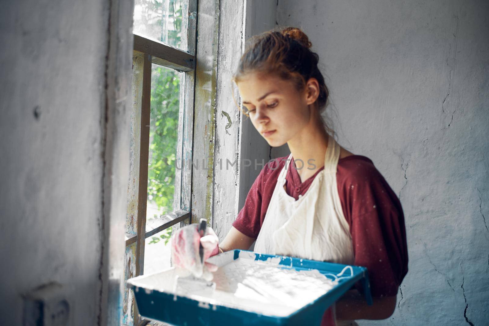 woman in apron painter repair painting window. High quality photo