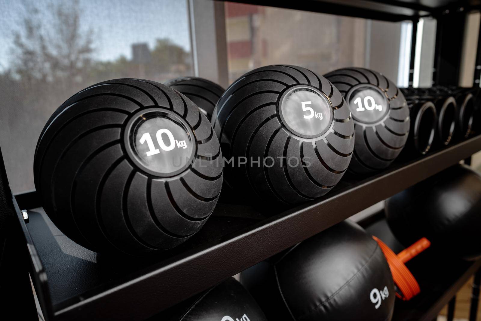 Balls and foam roller sport equipment in a gym on shelf
