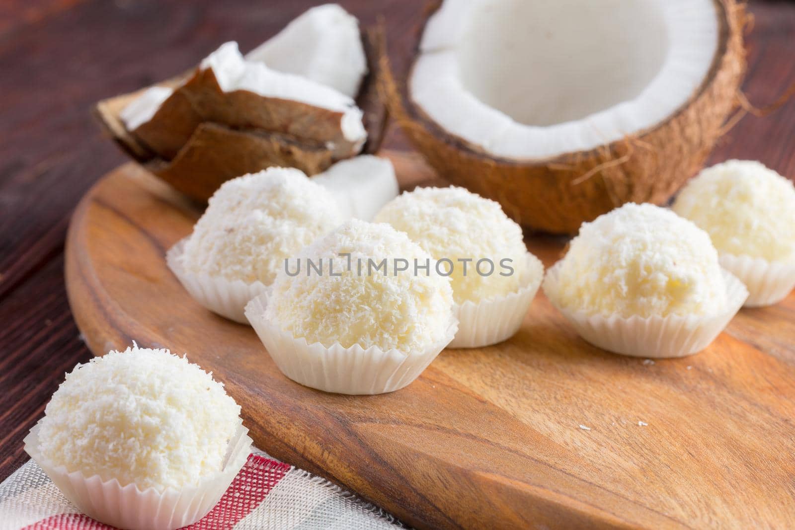 White chocolate candies with coconut topping close up on wooden table