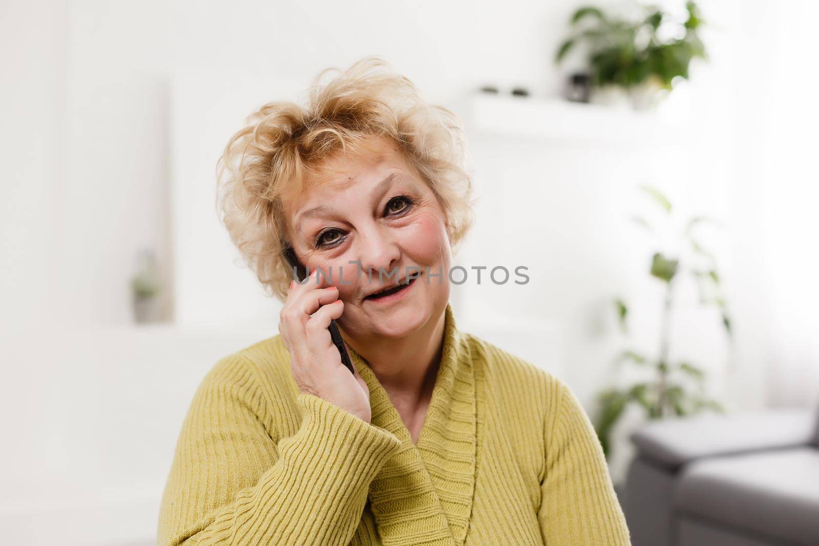 Concept of easy, fast usage of modern technology among all ages. Portrait of confident mature woman with wrinkles she is using her modern smartphone for sending a message isolated on gray background