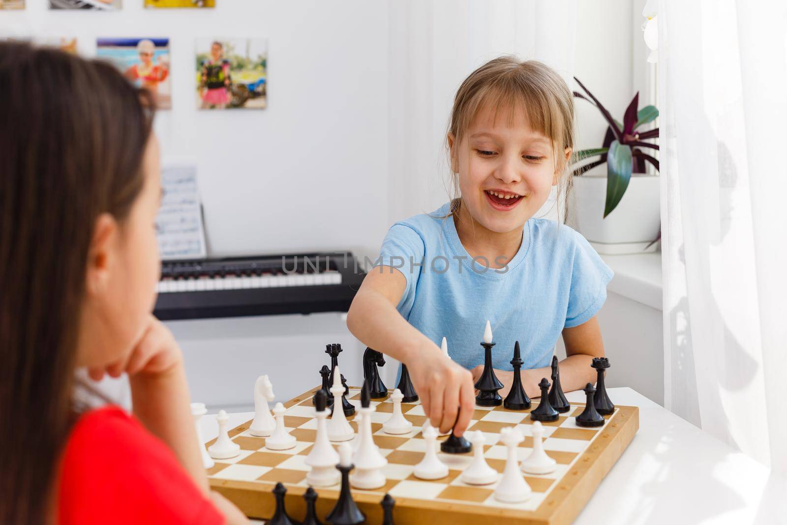 Two little sister playing chess at home by Andelov13